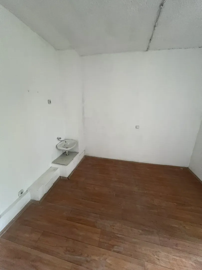 Prazna prostorija sa svijetlim zidovima, laminatom i malim umivaonikom.