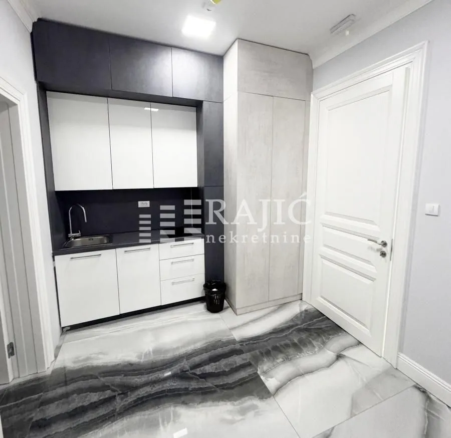 Small kitchen with white and dark cabinets and marble tiles.
