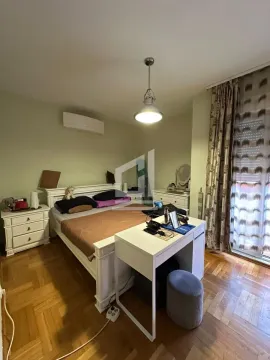 Spavaća soba sa bračnim krevetom, radnim stolom i parketom na podu. - image 7
