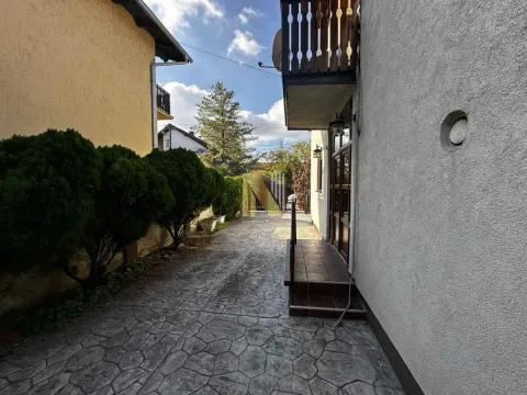 Popločano dvorište ispred kuće sa uređenim rastinjem i prilazom. - image 9