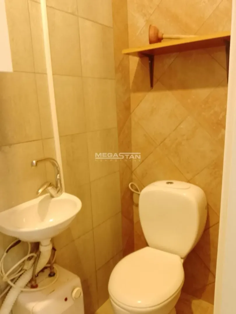Small tiled bathroom with a toilet and a sink.