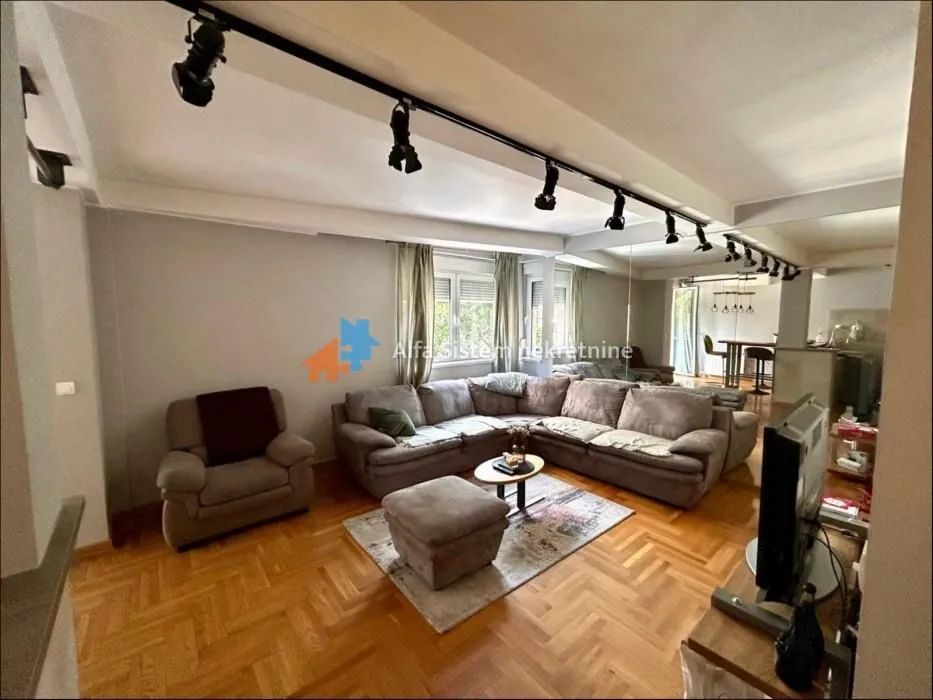 Spacious living room with a sectional sofa, armchair, and dining area in the background.