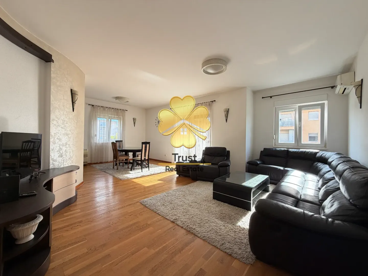 Spacious living room with a sofa set, dining table, and hardwood flooring.