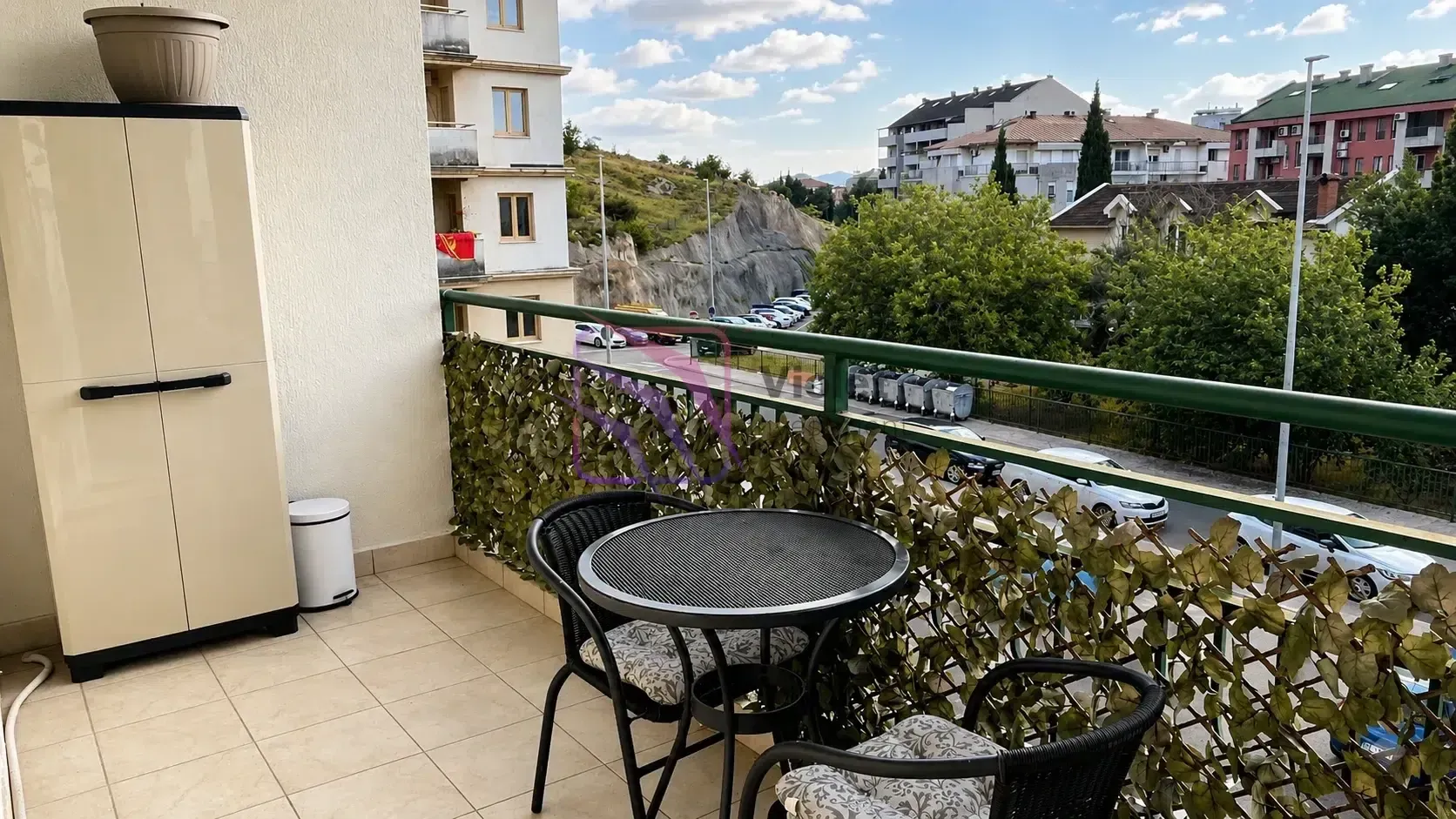 Namješten balkon sa stolom, stolicama i ormarićem.
