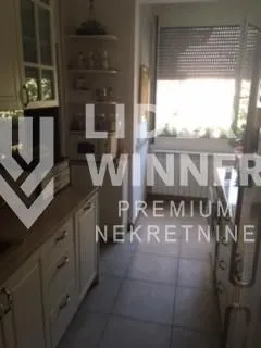 Manja svetla kuhinja sa belim elementima i prozorom.