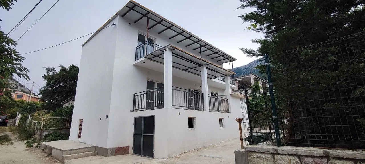 View of a white two-story house with balconies and a yard.