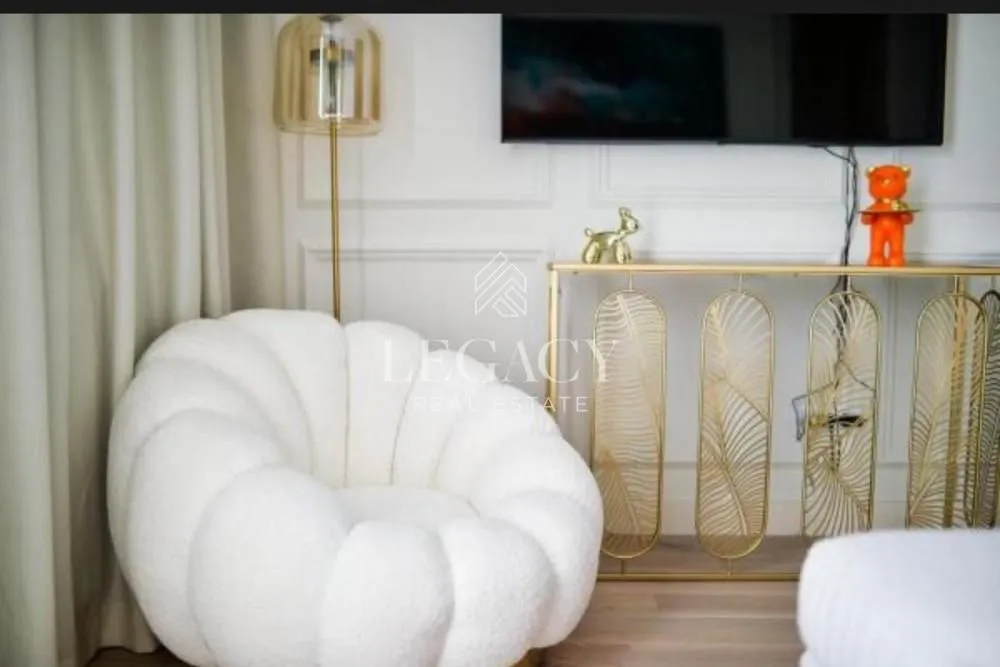 Udobna dnevna soba sa foteljom, konzolnim stolom i televizorom na zidu.