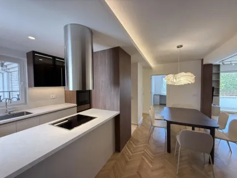 Modern kitchen with a breakfast bar opening into the dining area with parquet flooring. - image 6