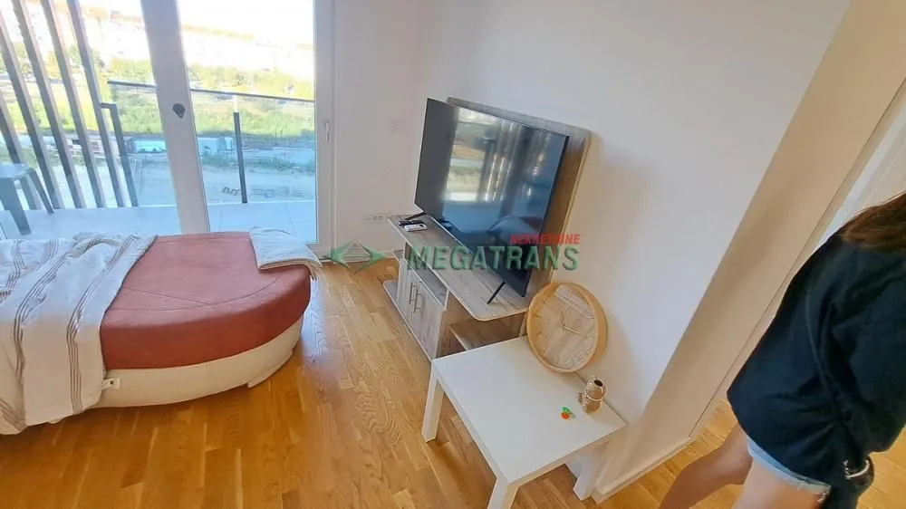 Pogled na deo spavaće sobe sa krevetom i televizorom.