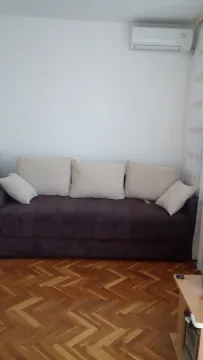 Dnevna soba sa tamnom garniturom, parketom i klima uređajem na zidu. - image 5