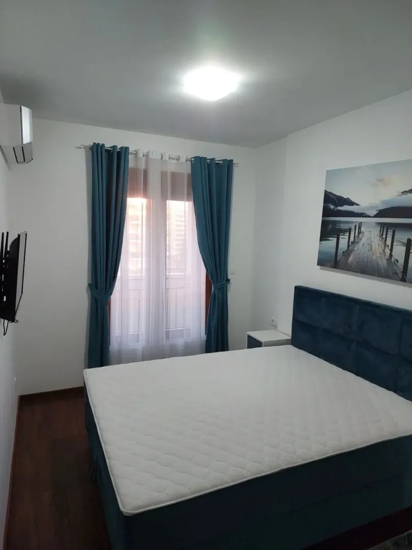 Bedroom with a double bed, blue curtains, and a wall painting.