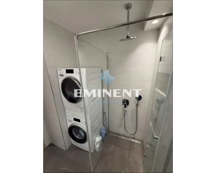 Modern bathroom with a walk-in shower and washing machine.