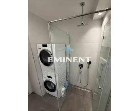 Modern bathroom with a walk-in shower and washing machine. - image 15