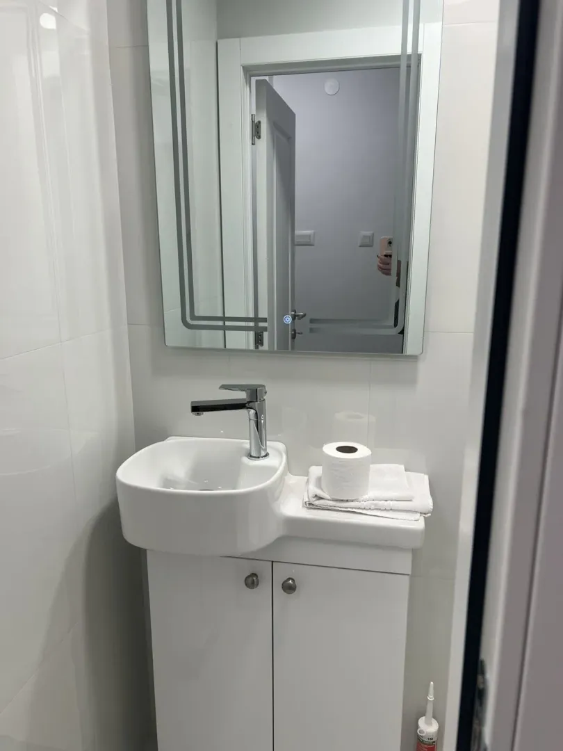 A small bathroom featuring a white sink and mirror.