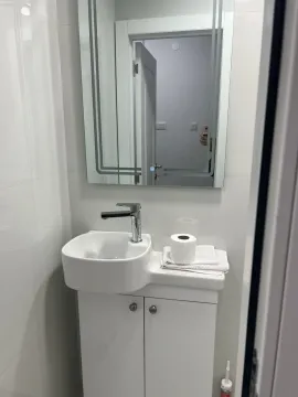 A small bathroom featuring a white sink and mirror. - image 17