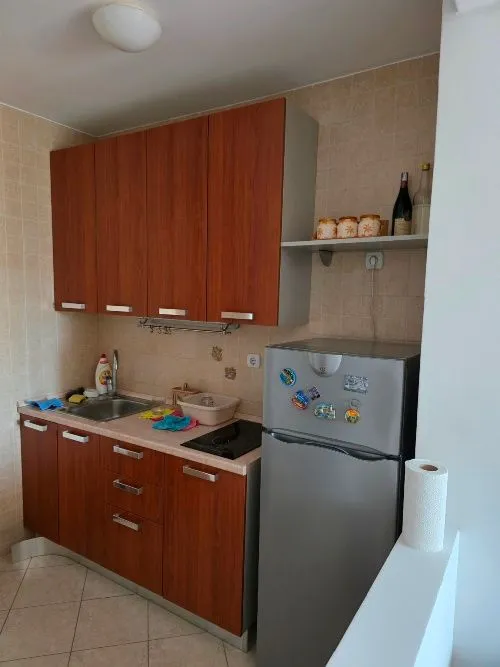 Manja kuhinja sa drvenim elementima i frižiderom.