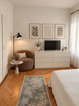 Furnished bedroom with a bed, dresser, armchair, and parquet flooring. - image 2