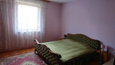 Spavaća soba sa bračnim krevetom, prozorom sa zavjesama i tepihom. - image 3