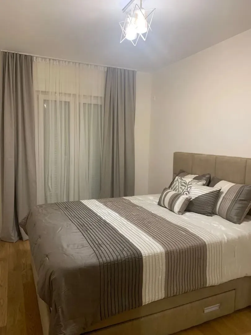 Furnished bedroom with a double bed and a window with curtains.