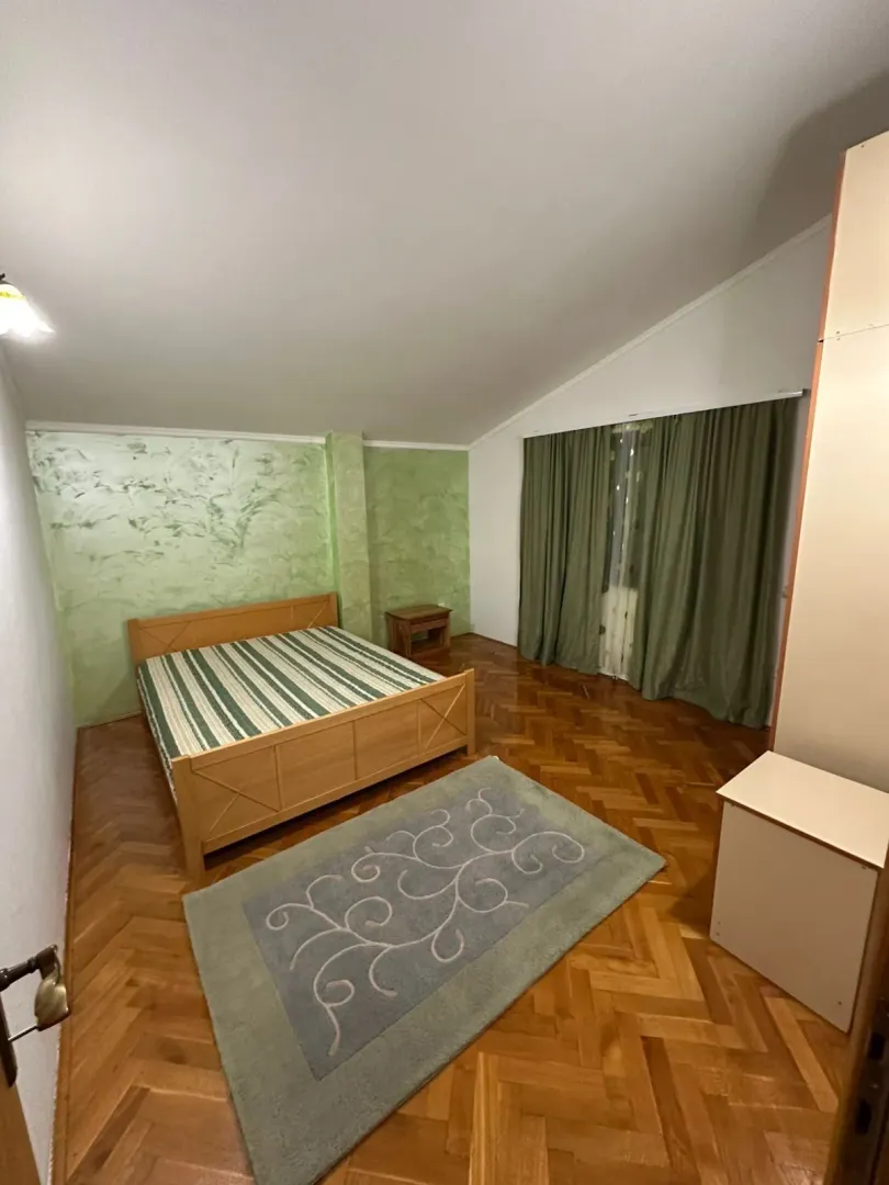 A simple bedroom with a wooden bed and a green accent wall.