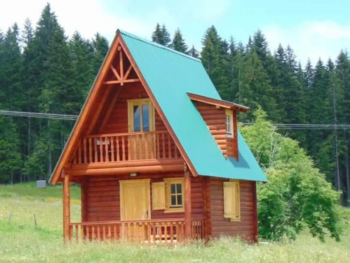 View of a wooden cottage surrounded by nature and forest.