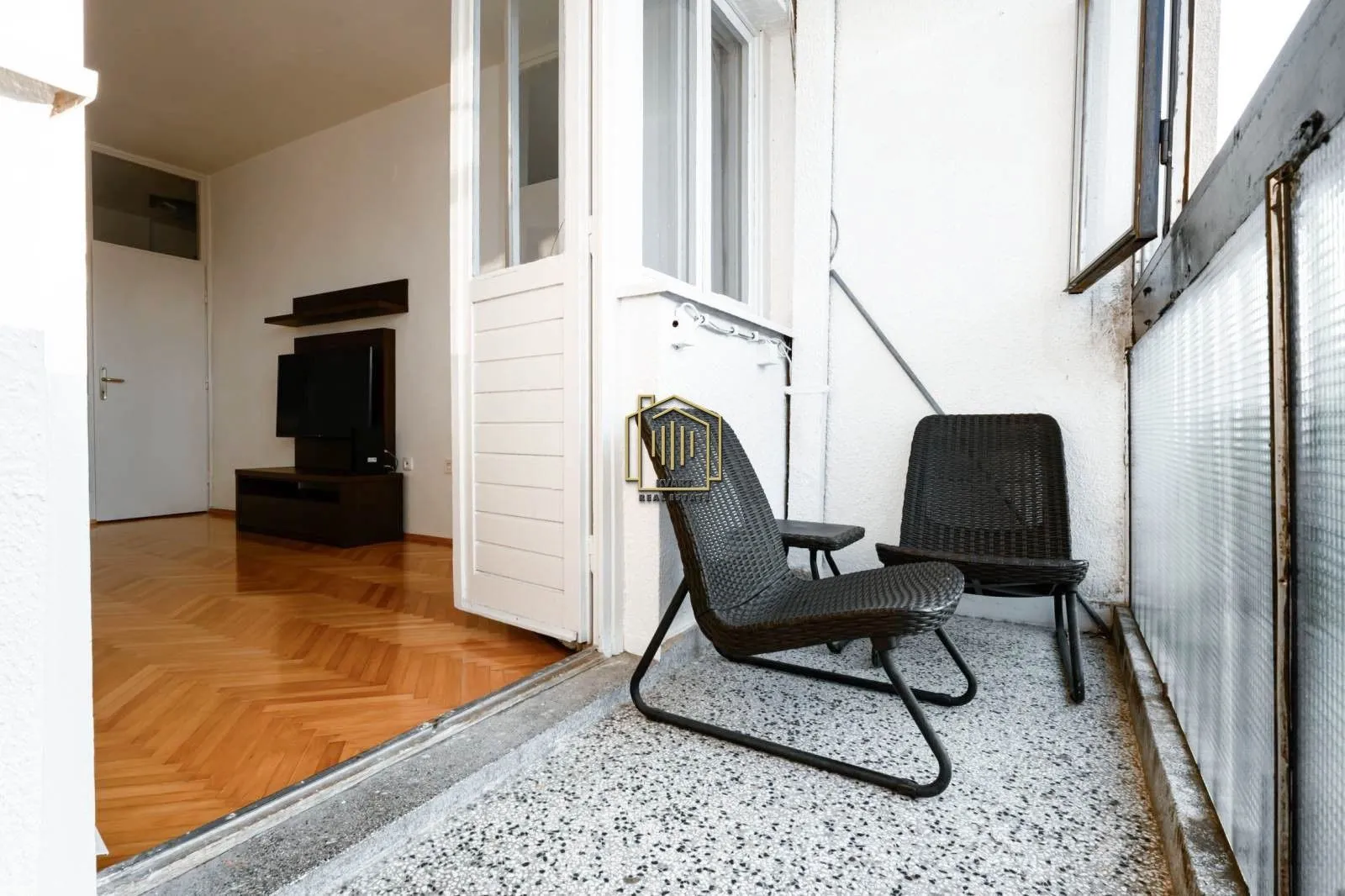 Natkriveni balkon sa garniturom za sjedenje i pogledom na unutrašnjost stana.