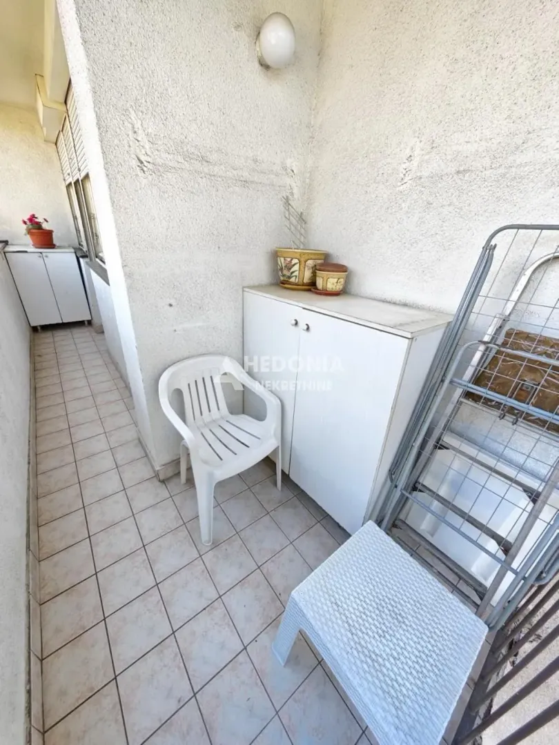 Manji zatvoreni balkon sa keramičkim pločicama i nameštajem.