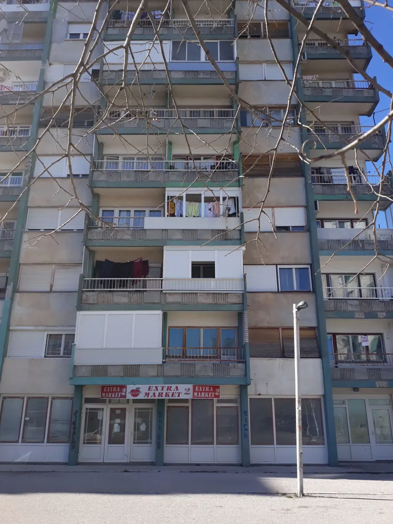 Exterior view of an older residential building with commercial space on the ground floor.