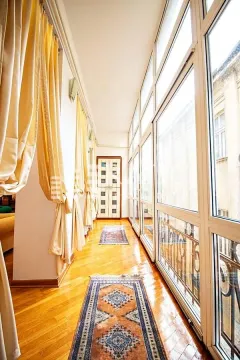 Enclosed balcony with wooden flooring and rugs. - image 14