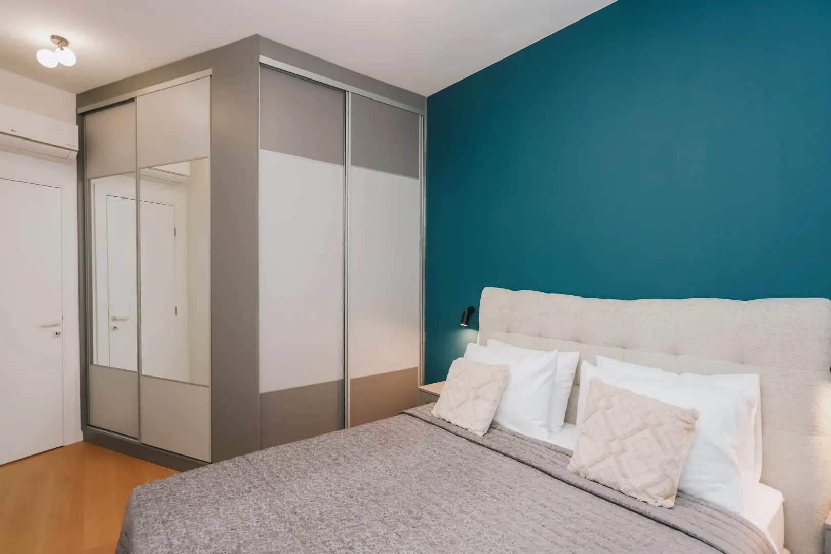 Modern bedroom with a double bed, large wardrobe, and a blue accent wall.