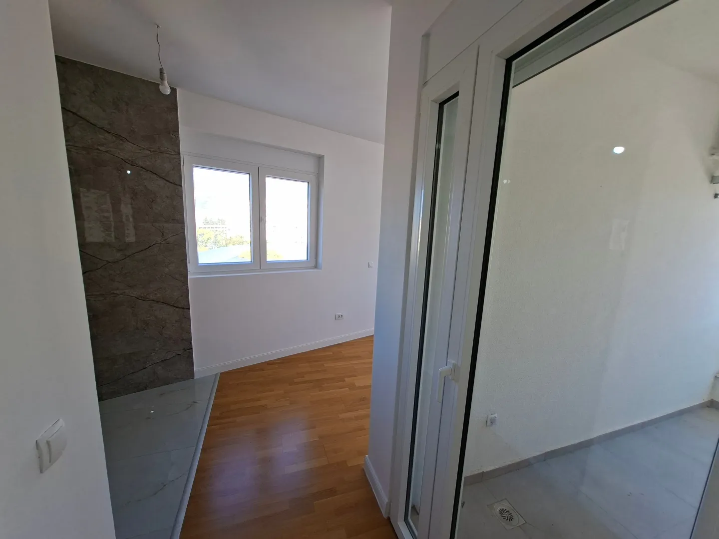 Empty room with parquet flooring, ceramic details, and terrace access.