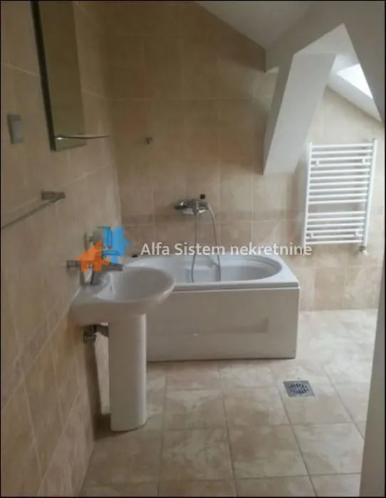 Bathroom tiled with ceramic tiles featuring a bathtub, washbasin, and towel radiator.
