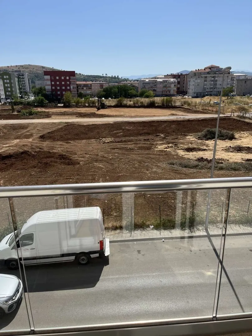 View from a balcony overlooking a construction plot and surrounding buildings.