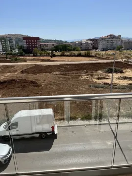 View from a balcony overlooking a construction plot and surrounding buildings. - image 2