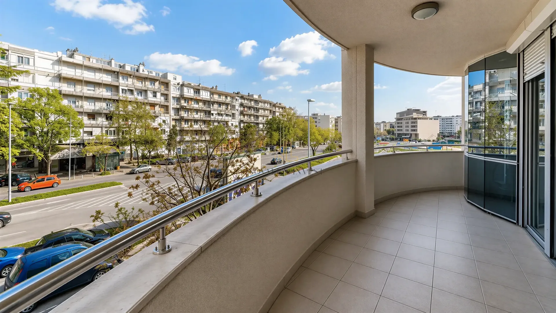 Spacious tiled balcony with a view of the street and surrounding buildings.