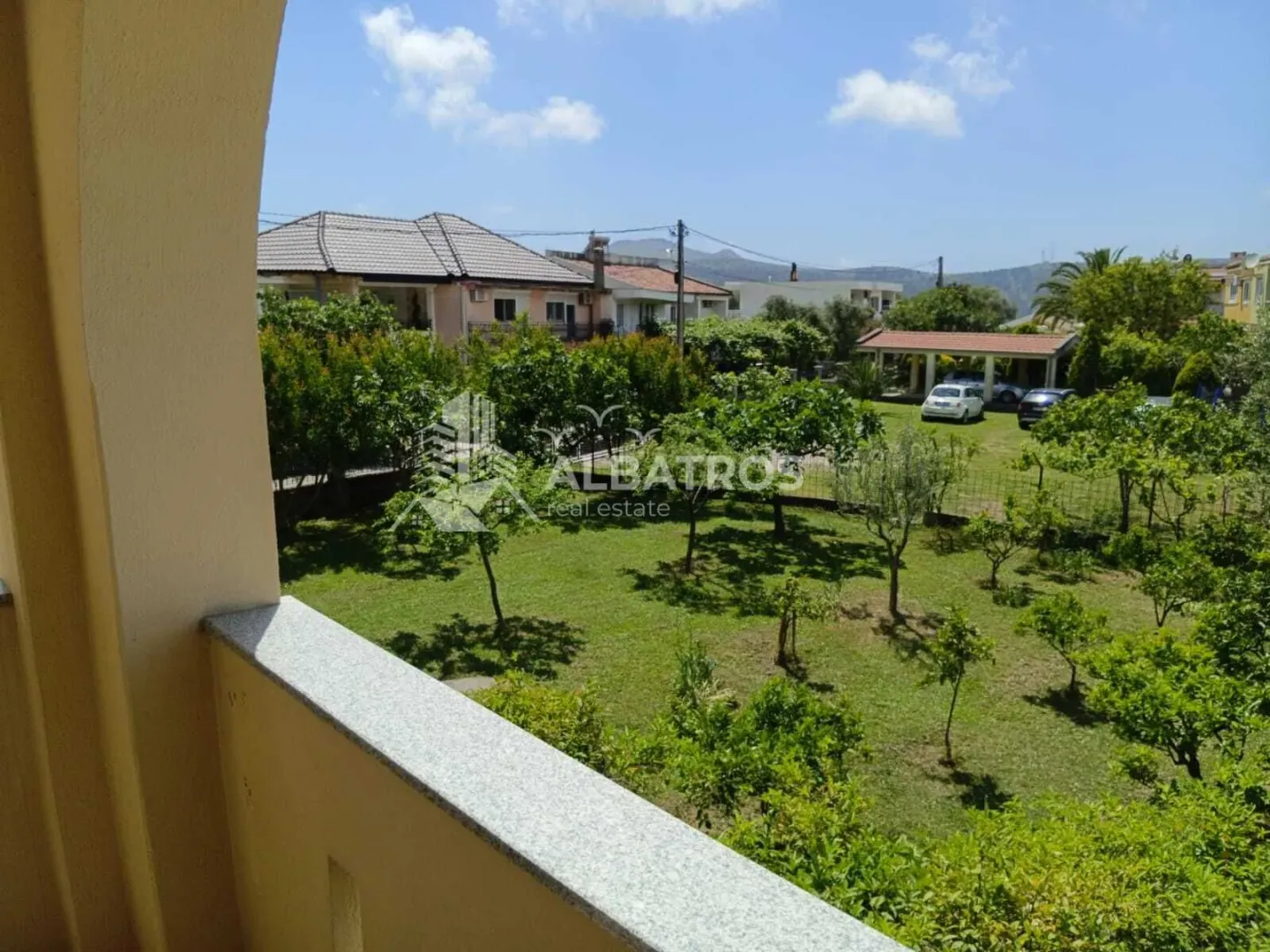 View from the balcony overlooking the green yard and surrounding houses.