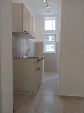 A small kitchen with light-colored cabinets and a window in the background. - image 5