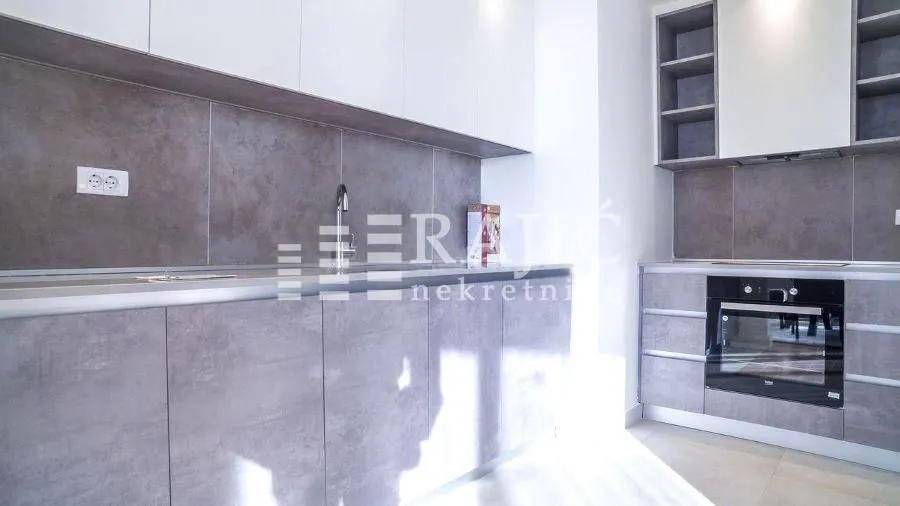Modern kitchen with grey cabinets and a built-in oven.