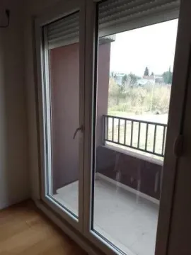 View through a balcony door showing a small terrace with a metal railing. - image 4
