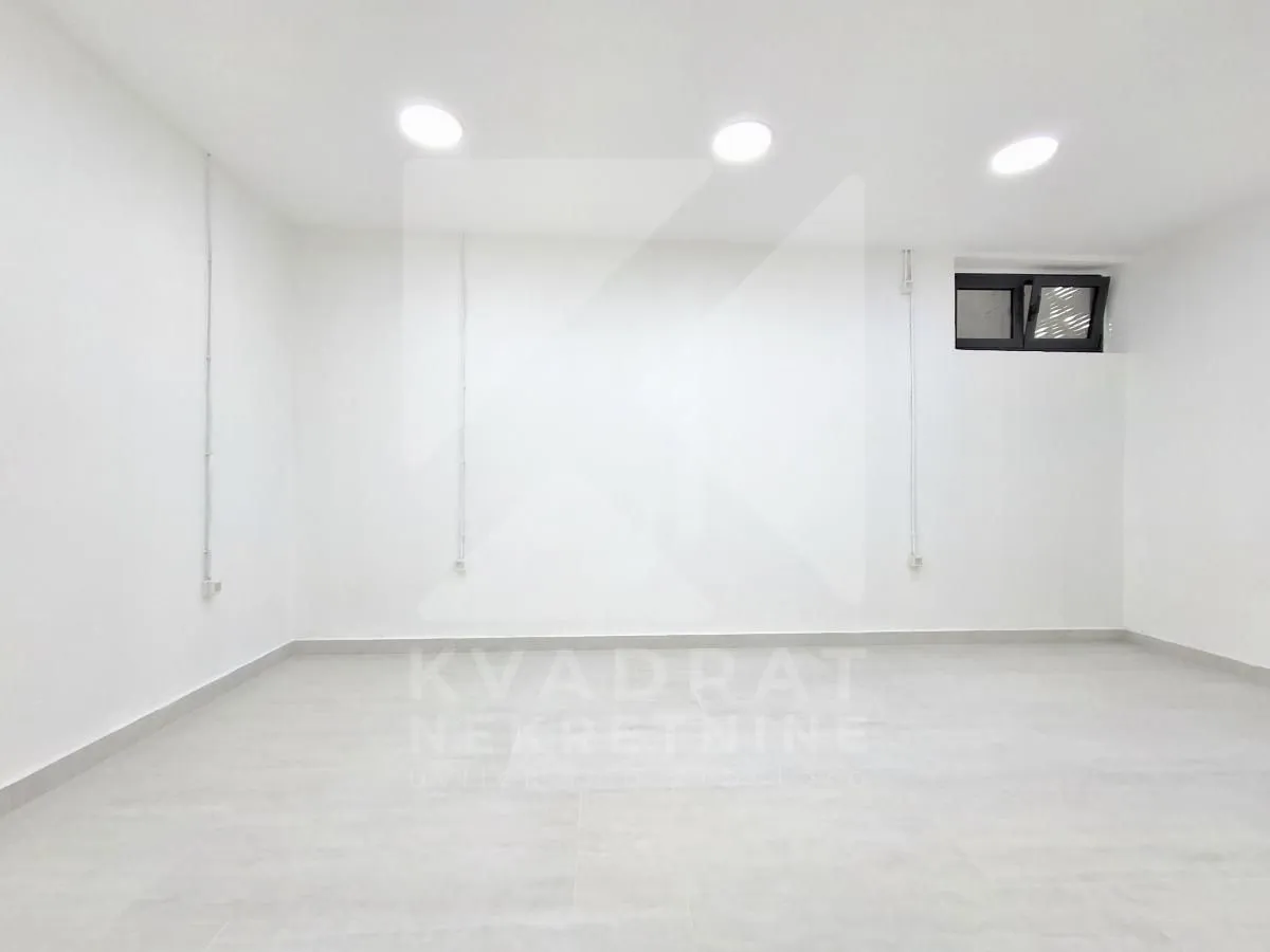 Empty bright room with white walls and a small window near the top.