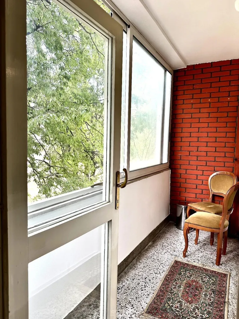 Zatvorena terasa sa dvije stolice i zidom od cigle.