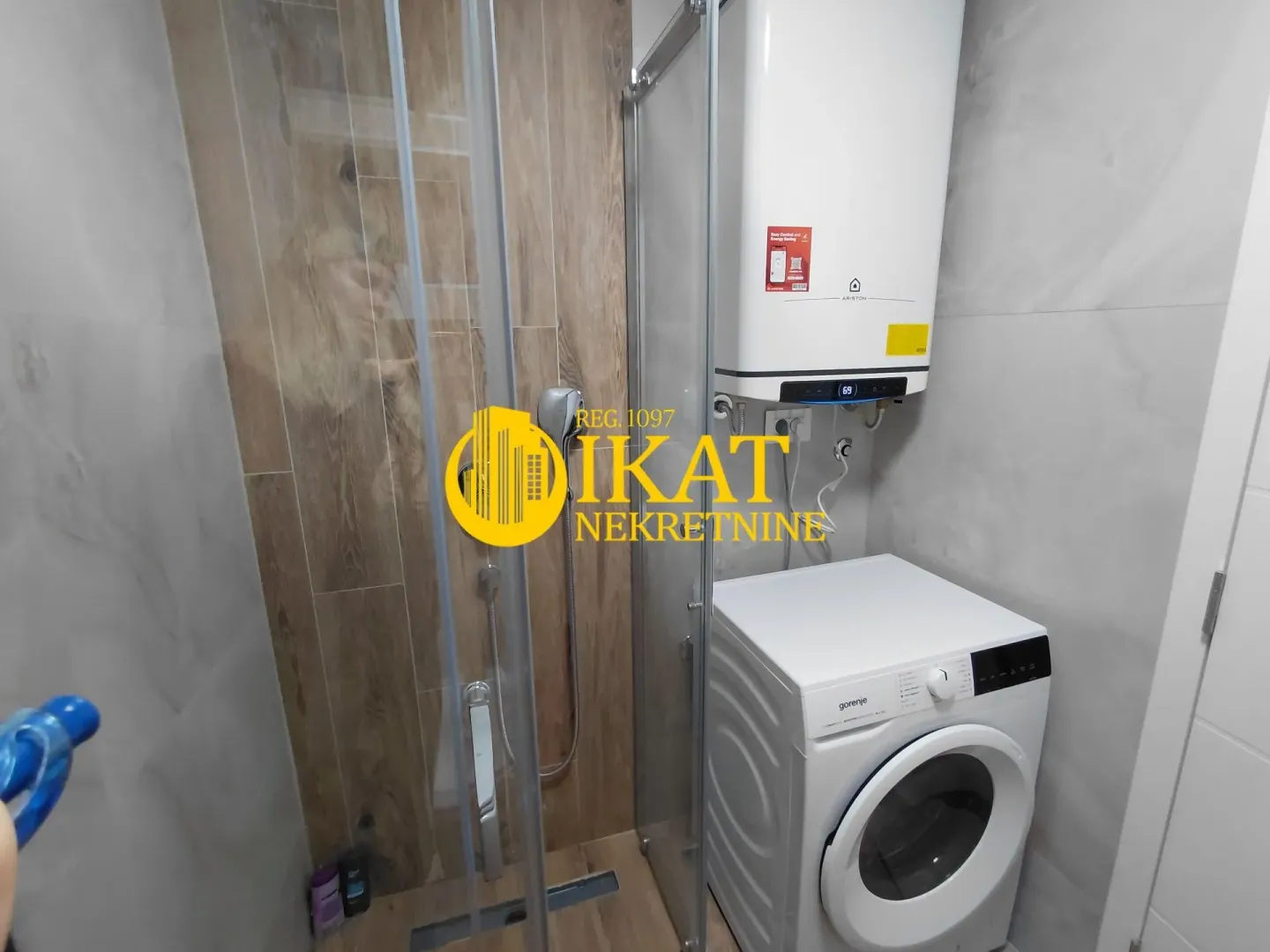 Bathroom with a shower cabin, water heater, and washing machine.