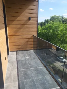Moderan i prostran balkon obložen pločicama sa staklenom ogradom. - image 2