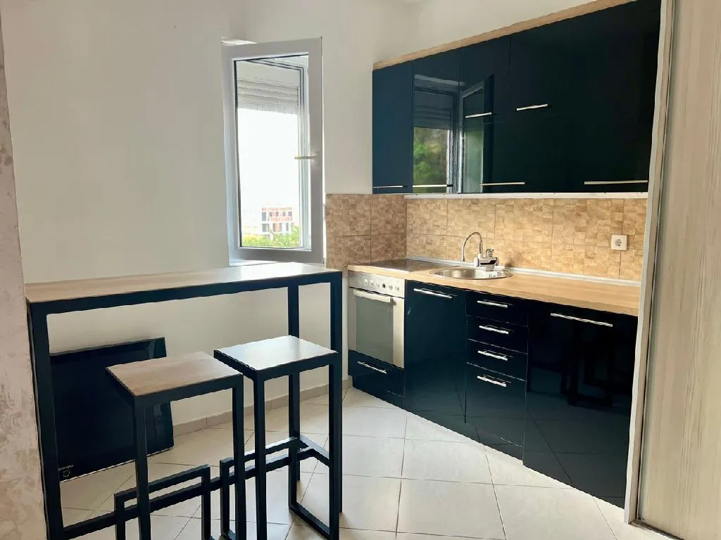 Small kitchen with black cabinets and a bar table with two stools.