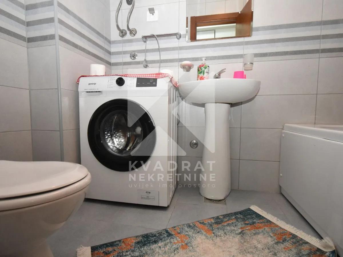 Kupatilo opremljeno umivaonikom, WC šoljom, mašinom za veš i kadom.