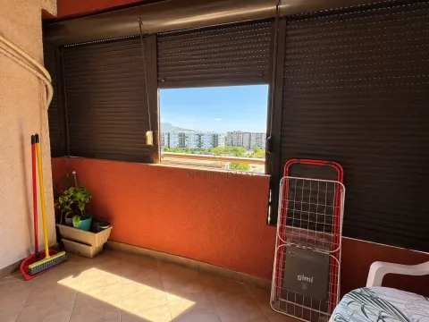 Covered balcony with lowered roller shutters and city view. - image 4