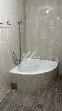 Kupatilo opremljeno ugaonom kadom i keramičkim pločicama na zidovima. - image 2