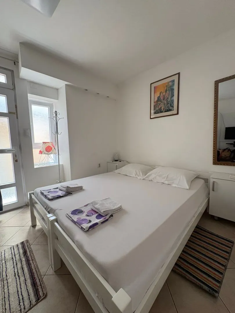 Spavaća soba sa bračnim krevetom i bijelim namještajem.
