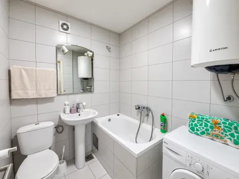 Bathroom equipped with a bathtub, washbasin, toilet, and washing machine. - image 5