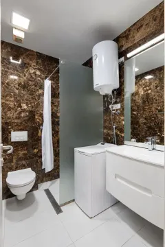 Modern bathroom with a walk-in shower, washbasin, and washing machine. - image 10